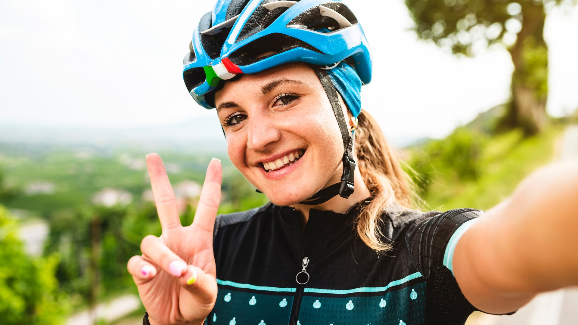 Female cyclist celebrating a successful ascent with a peace sign.