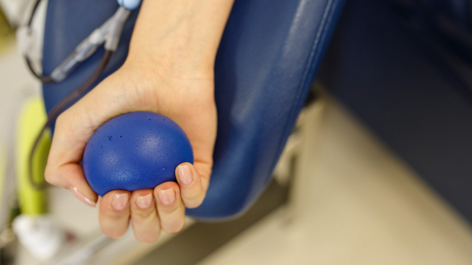Close-up of a cyclist's hand squeezing a stress ball while donating blood.