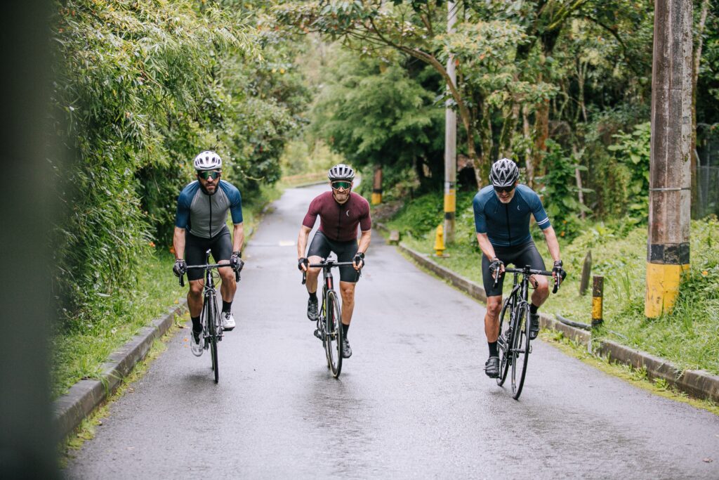 Three cyclists navigating a rainforest road in synchrony.