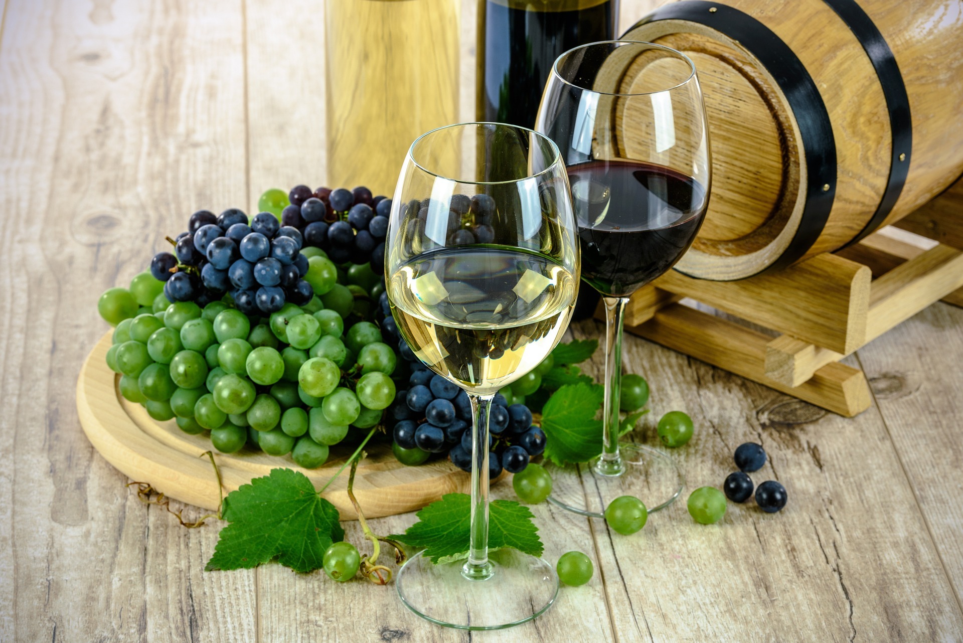 Two wine glasses alongside fresh grapes with a backdrop of a wooden wine barrel, showing a balance between alcohol and cycling performance