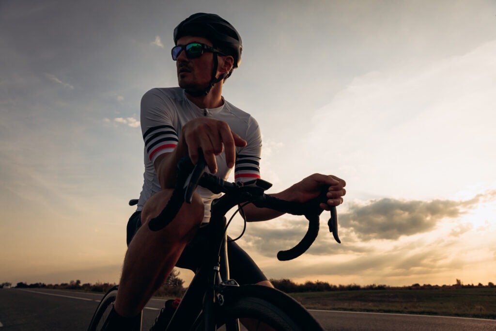 A silhouette of a determined cyclist against a dusky sky, focused on maintaining an optimal pace during an ultra-endurance ride.